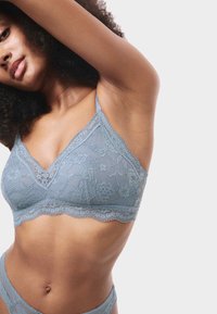 Bralette in pizzo di un delicato blu con motivi floreali, bordi curvi, spalline regolabili e design a scollo a V.