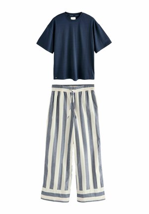 Marinblå kortärmad t-shirt med rund halsringning ovanför beige och marinblå randiga vida byxor med elastisk midja och dragsko.