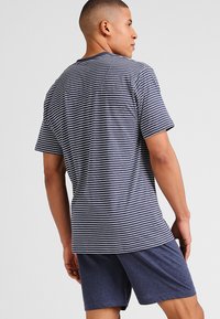 T-shirt in cotone blu navy a righe con maniche corte, abbinato a pantaloni corti blu navy. Presenta righe orizzontali bianche e una vestibilità comoda.