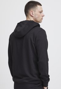 Felpa nera con una vestibilità comoda, dotata di un ampio cappuccio e maniche lunghe. Tessuto morbido con polsini e fondo a costine. Design minimalista.