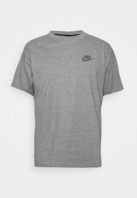 Šedé tričko s krátkým rukávem vyrobené z měkké bavlny, s malým černým logem Nike na levé části hrudníku. Klasický design s kulatým výstřihem.