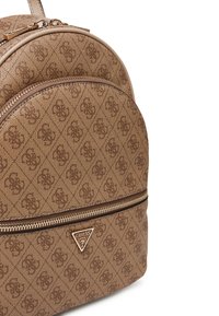 Brązowy plecak w wzory, wykonany z teksturowanej tkaniny, z zapięciem na zamek błyskawiczny i metalową tabliczką z logo, o zaokrąglonym kształcie i z wieloma przegródkami.