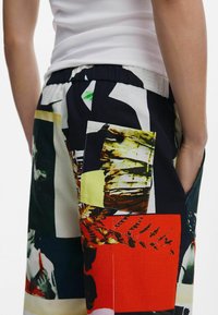 Patchwork-shorts har en blandad materialdesign med livfulla färger, texturerad tyg, elastisk midja och funktionella sidofickor.