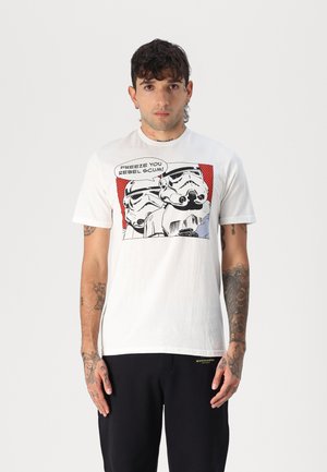 White cotton t-shirt with a graphic print featuring two stormtroopers and text "FREEZE YOU REBEL SCUM!" Set against a red background.