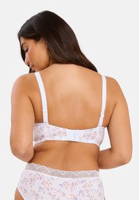 Soutien-gorge à motif floral blanc avec des bretelles réglables, dentelle sur les bords et fermeture à crochet au dos. Tissu doux avec une texture lisse.