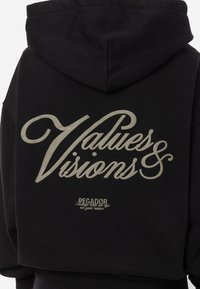 Felpa nera con cappuccio con grande testo bianco "Valori e Visioni" sul retro. Presenta un cappuccio con cordini e una texture di tessuto morbido. Logo piccolo in fondo.