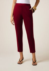 Bordeaux op maat gemaakte broeken met een slim fit, voorzien van zijzakken en een gladde textuur. Gekleed met zwarte flip-flops.