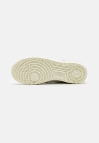 Suela de una zapatilla Nike blanca que muestra un patrón de trazado circular con bordes texturizados y el logotipo de Nike embellecido en el centro.