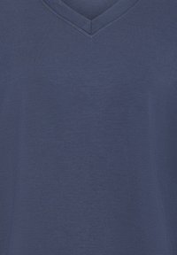 Chemise bleue à col en V avec manches courtes et texture de tissu lisse.