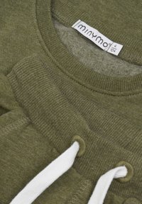 Olivgrüner Sweatshirt mit gerippten Bündchen und Ausschnitt. Mit weißen Kordeln und einem Etikett, das "minymo" sowie Größenangaben zeigt.