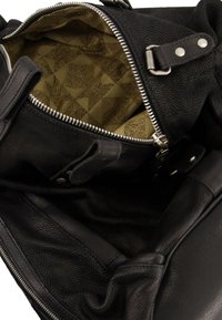 Zwarte leren tas met een open hoofdrits die een beige stoffen interieur met geometrisch patroon en details van zilverkleurige metalen hardware onthult.