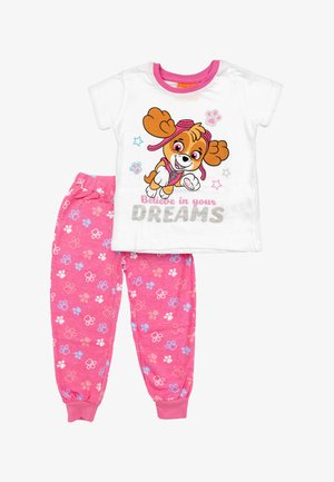 Chemise blanche à manches courtes avec un chien de dessin animé et le texte "Crois en tes rêves", associée à un pantalon rose à motifs d'empreintes de pattes.