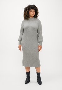 Vestido cinza em malha canelada com gola alta, mangas longas e silhueta reta, combinado com botas de tornozelo pretas. Tecido suave e texturado.