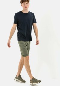 Navy crew-neck t-shirt paired with olive green shorts, featuring rolled cuffs and two side pockets, complemented by gray sneakers.