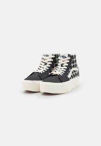Zwarte hoge sneakers met witte accenten, textuurstof en een gemêleerd zijontwerp. Dikke witte rubberen zool en veters.