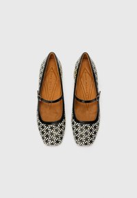 Black and white patterned flat shoes with a rounded toe, leather lining, and a Mary Jane strap. Smooth texture and contrasting accents.