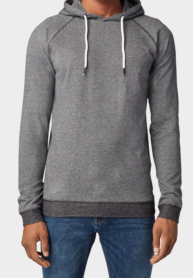 Grijze hoodie met een textuurpatroon, witte koordjes en een donkere ribbelrand. Lange mouwen en een ontspannen pasvorm, gecombineerd met denim jeans.