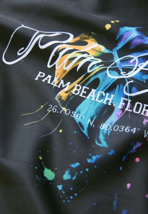 Zwarte stof met kleurrijke verfspatten, schrifttekst "Palm Beach, Florida," en geografische coördinaten in wit. Gladde textuur.