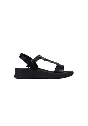 Sandalia negra de mujer con puntera abierta, correa ajustable en el tobillo, suela acolchada y detalle decorativo texturizado en forma de T.