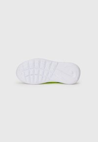 Semelle extérieure en caoutchouc blanc avec des motifs de grip texturés et des accents verts. Présente un talon plat et un logo Nike intégré dans la semelle.