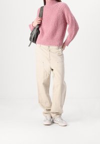 Rosa gestrickter Pullover mit hohem Kragen, beigen, lässigen Hosen und hellen Sneakern. Mit strukturiertem Stoff, oversized Ärmeln und seitlichen Taschen.