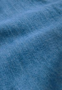 Lichtblauwe stof met een gladde textuur, met fijne weefdetails. Het lijkt katoen of een vergelijkbaar materiaal met een zachte afwerking te zijn.