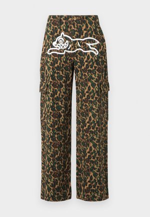 Maskáčové kalhoty s širokými nohavicemi mají v přední části v oblasti pasu bílého kresleného psa s ostrými zuby.