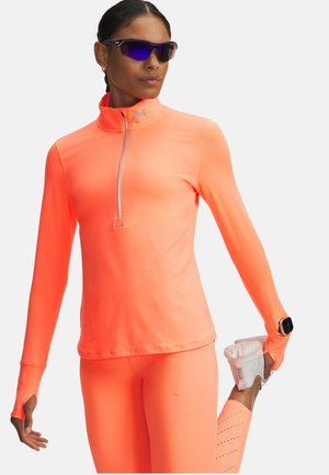 Neonoranje atletisch shirt met lange mouwen en een halve ritssluiting bij de kraag, gecombineerd met bijpassende legging en een smartwatch om de pols.