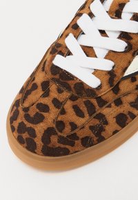 Sneakers med leopardprint, brun suedette overdel, hvide snørebånd og sål i gummigummi. Rund tå og glatte sømme langs syningerne.