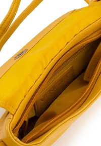 Kleine gelbe Lederhandtasche mit glatter Außenfläche, ausgestattet mit einem Reißverschlusstaschen und Markenbranding im Inneren. Sie hat eine lebendige, weiche Textur.