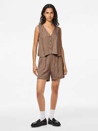 Brunrandig ärmlös topp med v-ringning och knappframsida, tillsammans med matchande brunrandiga shorts. Modellen bär svarta skor och vita strumpor.