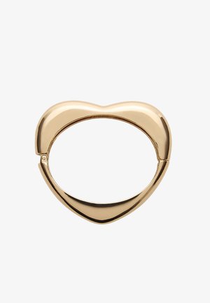 Pierścionek w kształcie serca w złotym odcieniu z gładką, błyszczącą powierzchnią i pustym wnętrzem. Posiada unikalny sposób zapięcia dla bezpiecznego zamknięcia.