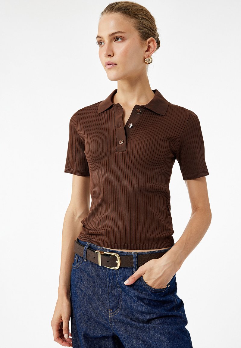 Brun ribbet polo t-shirt med korte ærmer, med krave og knaplukning med tre knapper; parret med blå denim jeans og et brunt bælte.