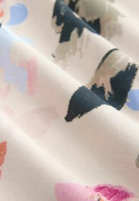 Material textil din bumbac cu fundal crem deschis și modele abstracte de tușe de pensulă în roz, albastru, verde și negru. Textură moale.