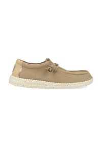 Zapato deslizante de tela color marrón con punta redondeada, parte superior texturizada y suela ligeramente moteada. Presenta un detalle decorativo de cordones y un interior suave.