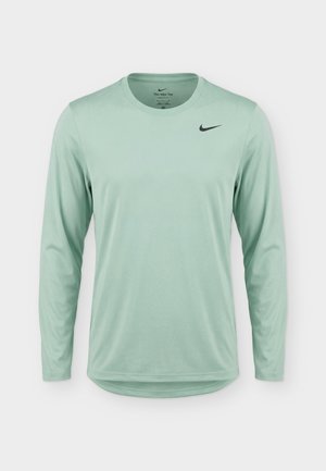 Jasnozielona sportowa koszulka Nike z długim rękawem, dekoltem typu crew neck i małym czarnym logo Nike swoosh na piersi.