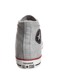 Baskets montantes grises Converse All Star vues de dos montrant le patch du logo et une bande rouge au-dessus de la semelle blanche.