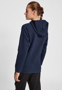 Felpa blu navy con cappuccio regolabile, texture morbida, maniche lunghe e vestibilità rilassata. Presenta polsini e orlo a costine per un tocco in più.