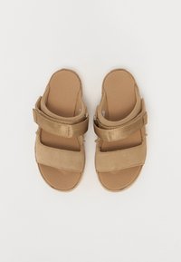 Brune sandaler med brede tekstilremmer og en strukturert fotseng. Designet har en polstret såle for komfort og delvis åpen tå.