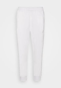 Bílé sportovní kalhoty s elastickým pasem, zakončením u kotníků a potištěným vzorem po stranách. Hladká tkanina s lehkým designem.