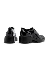 Pantofi din piele patent neagră cu vârful rotunjit, design cu șireturi și talpă groasă din cauciuc, având modele texturate pentru aderentă.