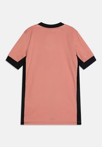Chemise à manches courtes en tissu corail doux, dotée d'un col noir et d'accents latéraux. Texture lisse avec des détails de couture minimaux.