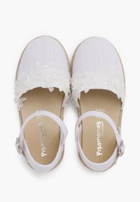Chaussures de style espadrille blanches avec une tige en tissu texturé, finition florale en dentelle et sangle de cheville ajustable, dotées d'une semelle en jute naturel.