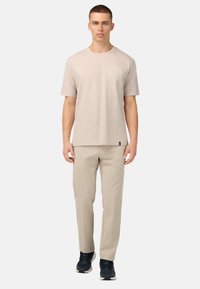 Ljusbeige t-shirt med bröstficka, kombinerat med ljusbeiga byxor. Bekväm passform med korta ärmar och en avslappnad stil.