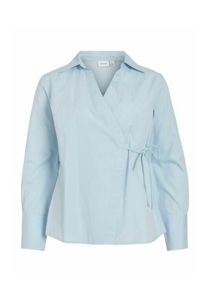 Blusa cruzada de manga larga en azul claro con cuello y cierre lateral de lazo, ajuste entallado y puños anchos.