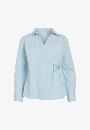 Blusa cruzada de manga larga en azul claro con cuello y cierre lateral de lazo, ajuste entallado y puños anchos.