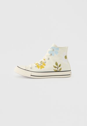 Høyanklet hvit sneaker med blå, gule og hvite blomstertrykk og grønne bladmotiver på lerretsmaterialet.