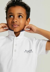 Biele polo tričko s námorníckou golierom, gombíkovou légou a vyšitou textom "BAKER BY TED BAKER." Hladká textura, krátke rukávy.