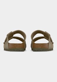 Καφέ σουέντ σανδάλια με διπλά λουριά, πάτο από φελλό και υφασμένα λαστιχένια πέλματα. Διαθέτουν διακοσμητικό φιόγκο σε ένα από τα λουριά.