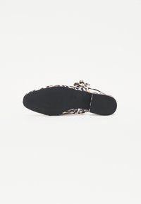 Musthave mustrid musta ja beežiga kaunistatud korterjalanõud, millel on tekstureeritud tallad, mitme ristuvate rihmadega ja kindel kinnitussüsteem.